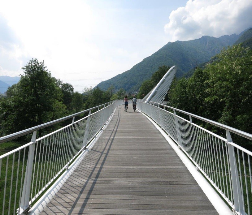 Due ciclisti passano sul ponte ciclabile.